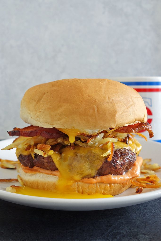 hangover burger recipe topped with hash browns, sunny side up egg, and bacon